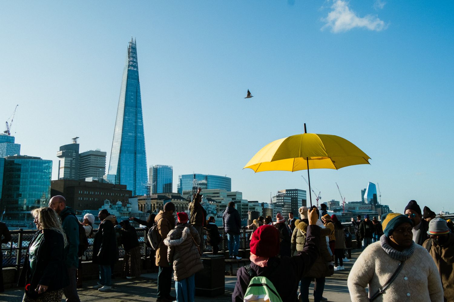 A yellow umbrella stands out against the London city skyline featuring the iconic Shard building on a sunny day.