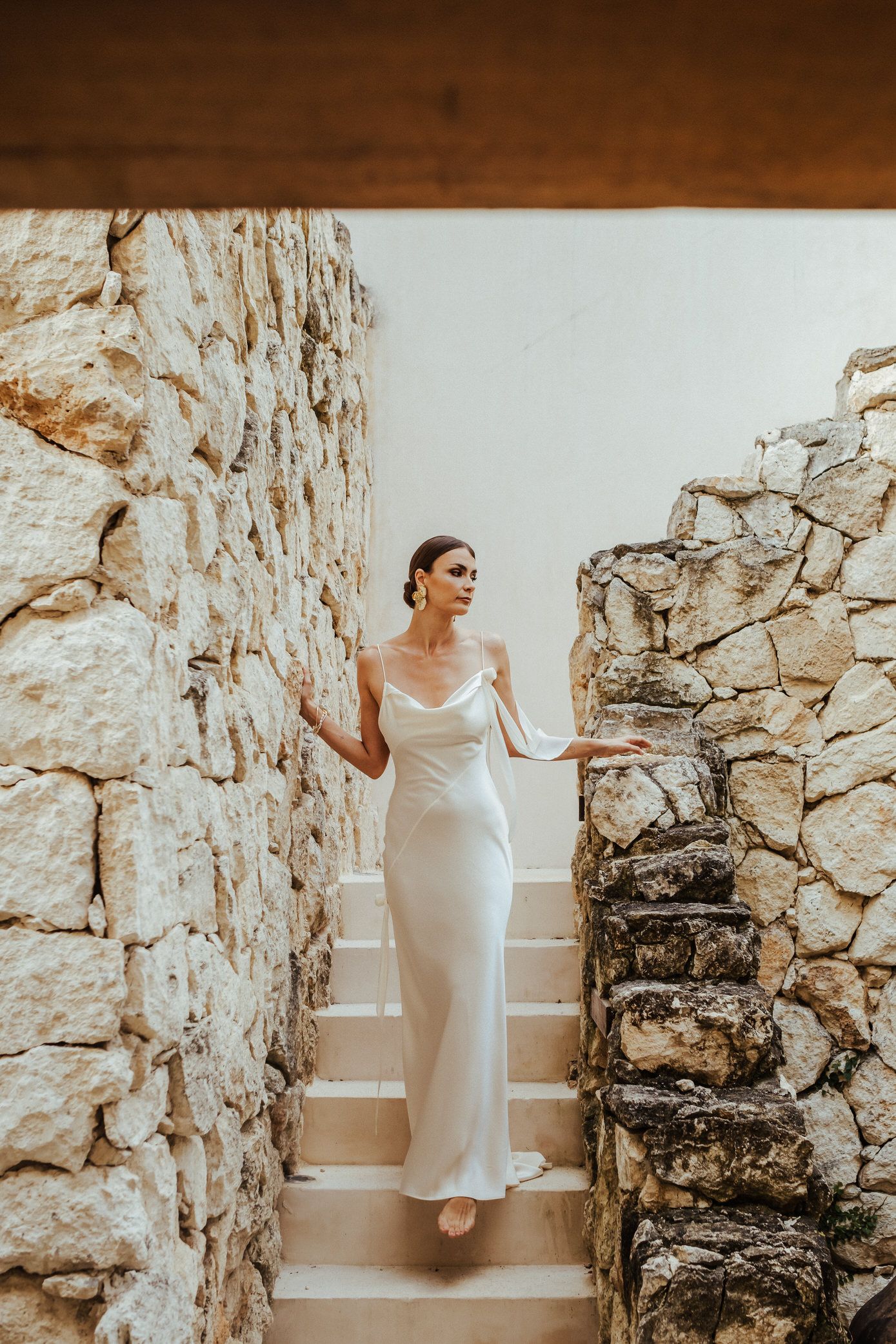A person in a white dress poses elegantly against rustic stone walls in a creative bridal photoshoot sequence.