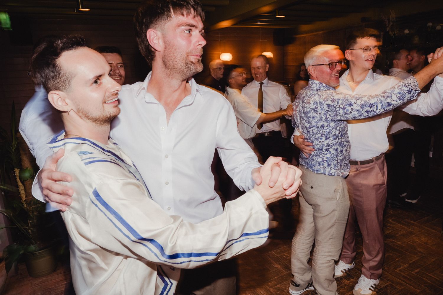 Couples dance together during a lively social gathering in a dimly lit venue.