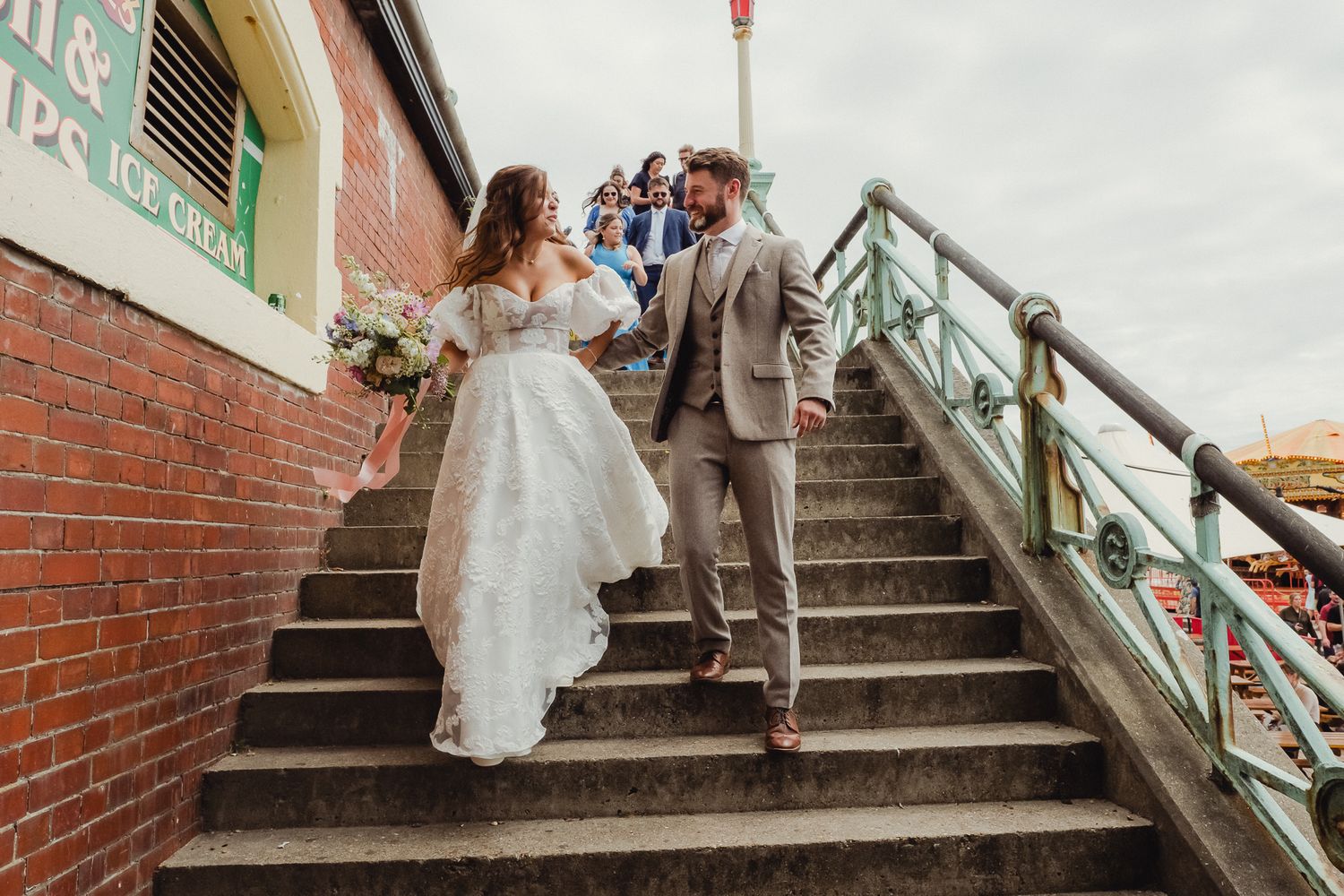 Newlywed couple descends brick staircase with green railing in series of romantic wedding day photos.