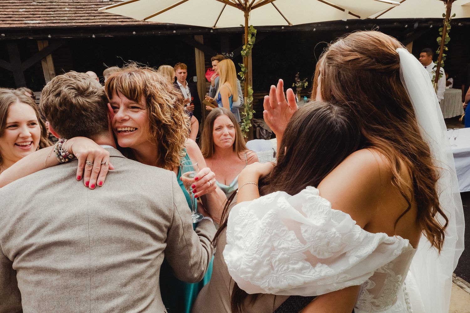 Wedding guests dance together in a line during a reception celebration under warm lighting.