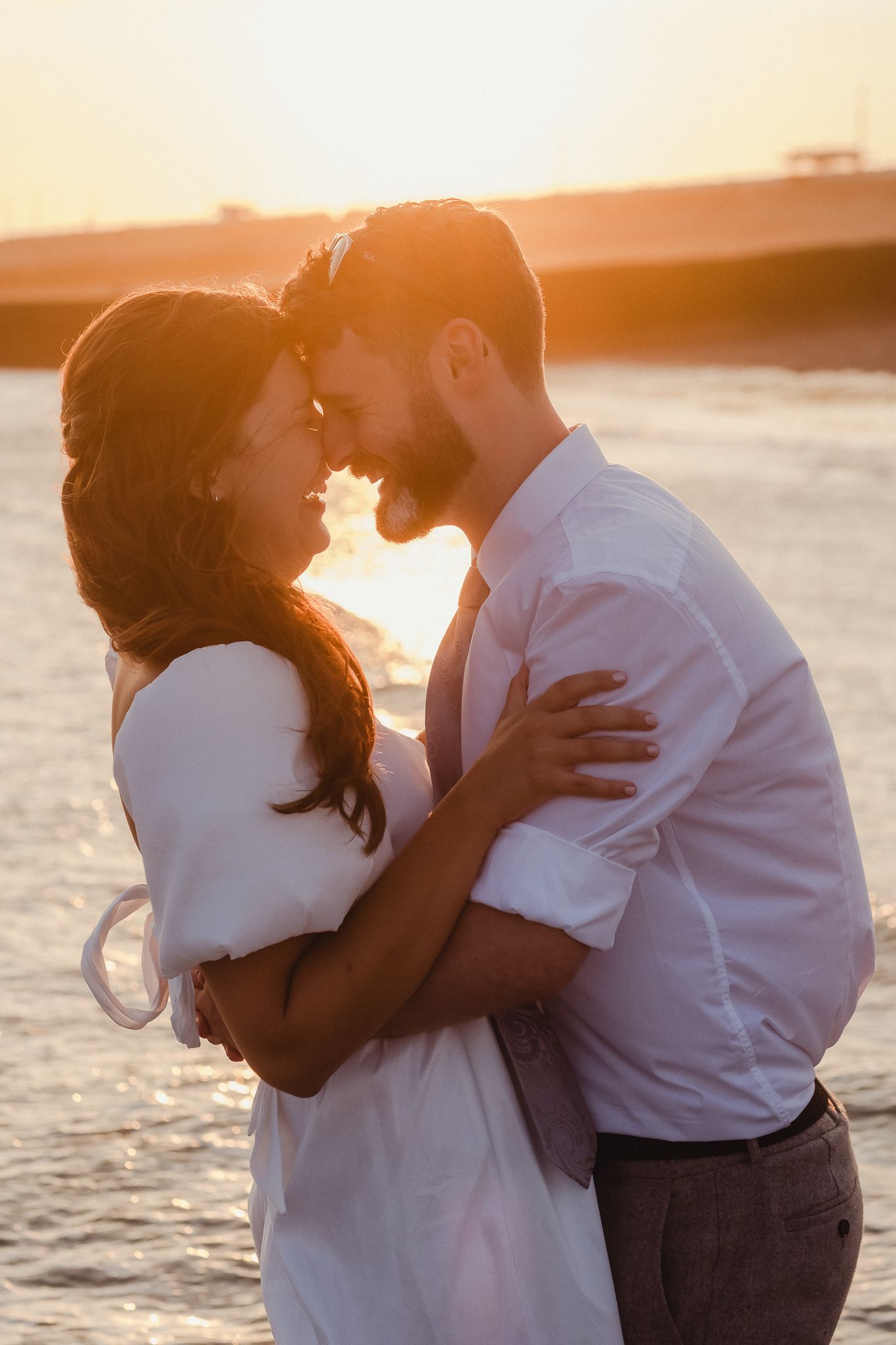 A couple embraces in a romantic silhouette against a golden sunset on the beach during a tender moment.