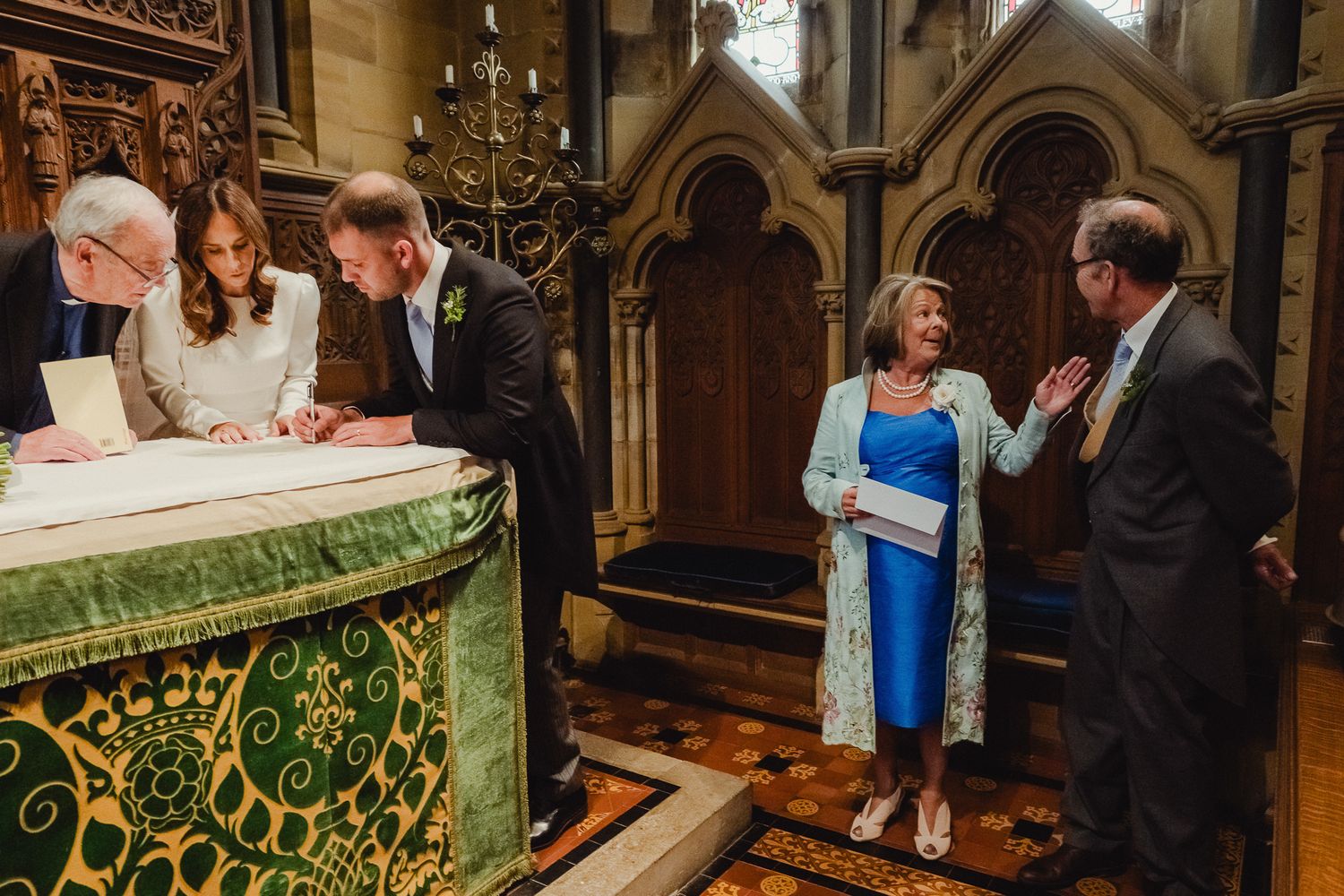 Wedding ceremony taking place in a historic church with ornate Gothic architecture and decorative altar cloth.