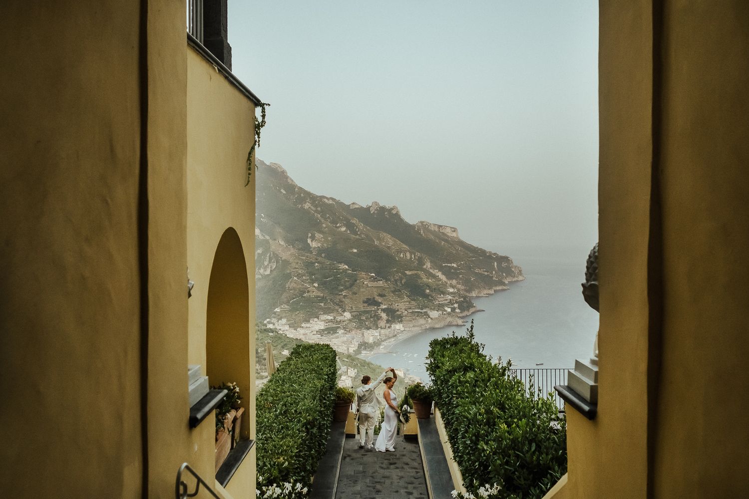 Mediterranean wedding venue with stone archways framing a coastal mountain view.