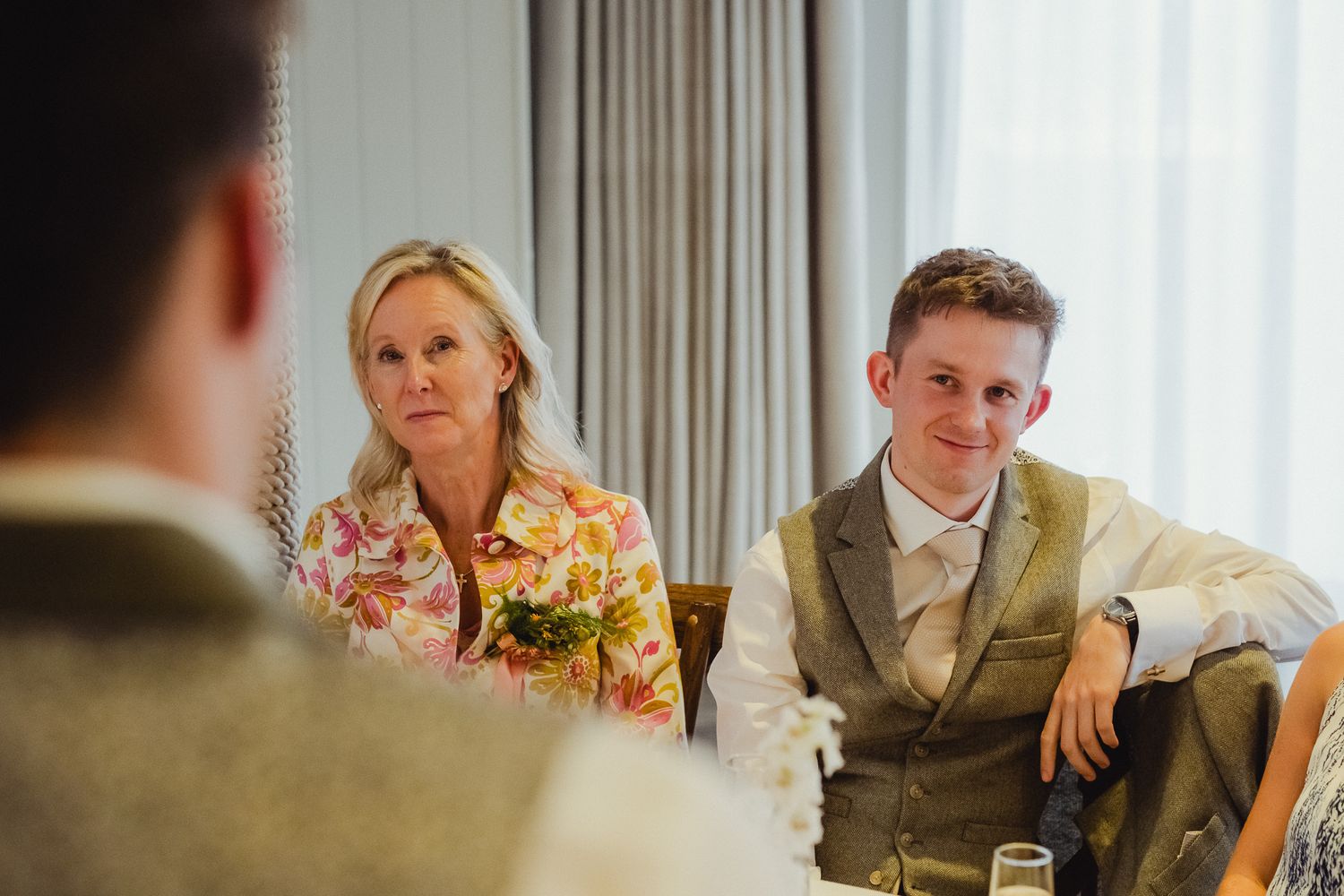 Wedding guests laugh and enjoy themselves during an indoor reception celebration at an elegant venue.
