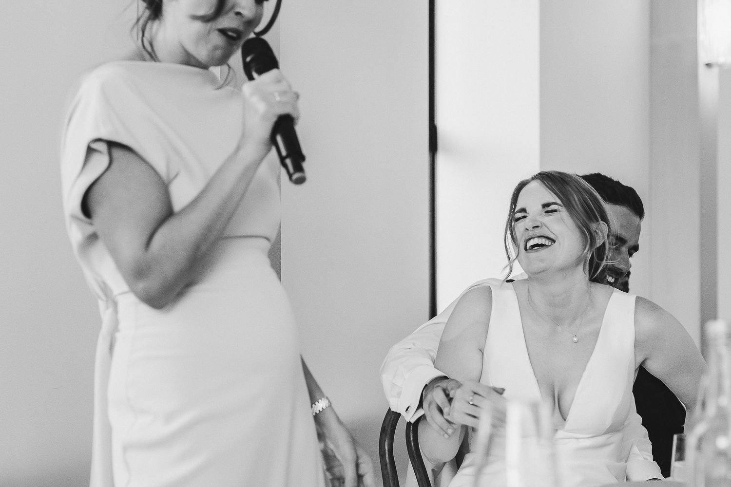 A group of people in white clothing laugh and dance together at a joyful celebration.