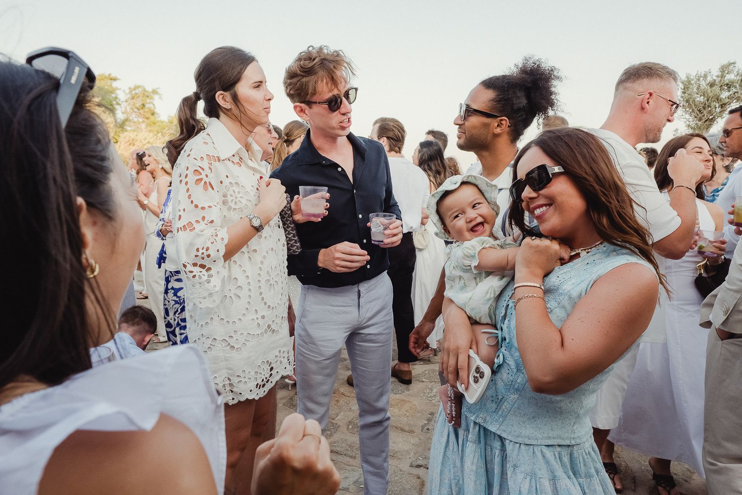 Group of wedding guests enjoying themselves at an outdoor celebration during sunset.