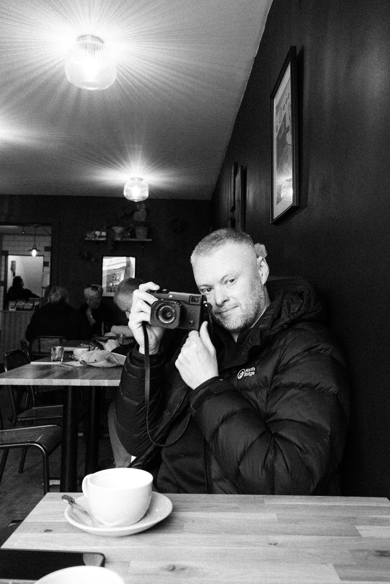 A series of black and white photos showing someone sitting at a table with a coffee cup in different contemplative poses.
