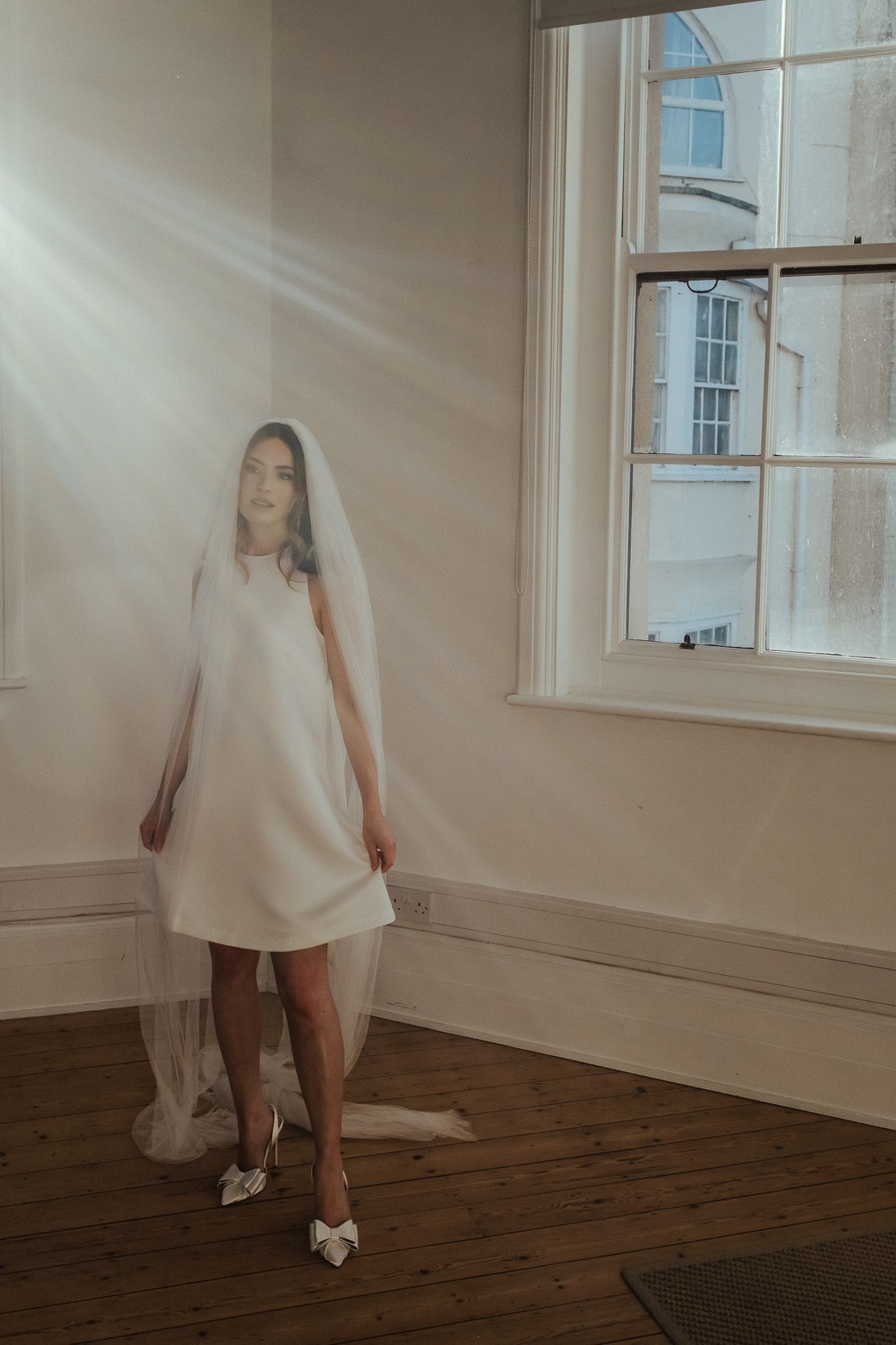 A series of five motion blur photographs showing a figure in a white dress and silver shoes against hardwood floors.