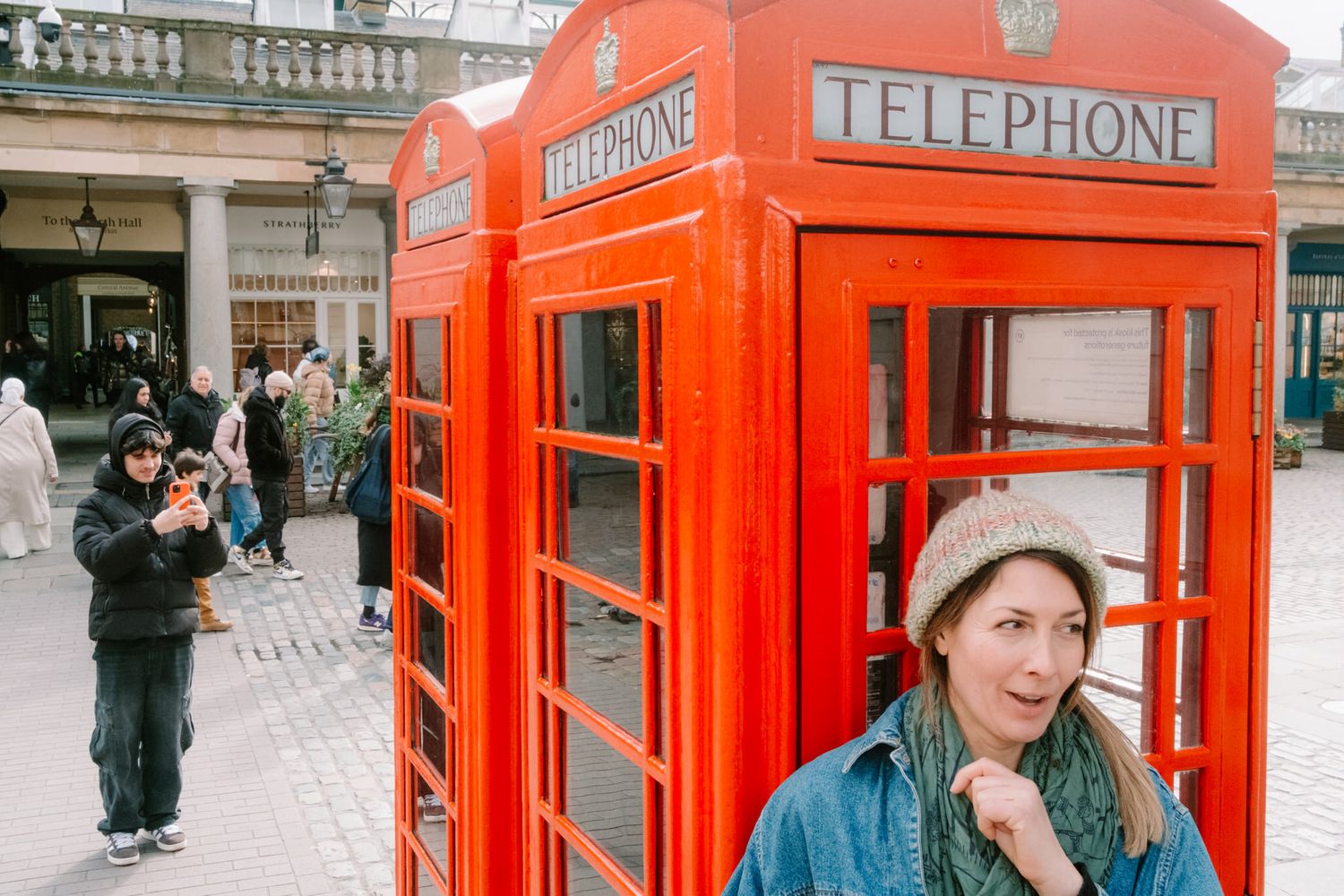 A series of iconic red British telephone boxes lined up on a street in London.