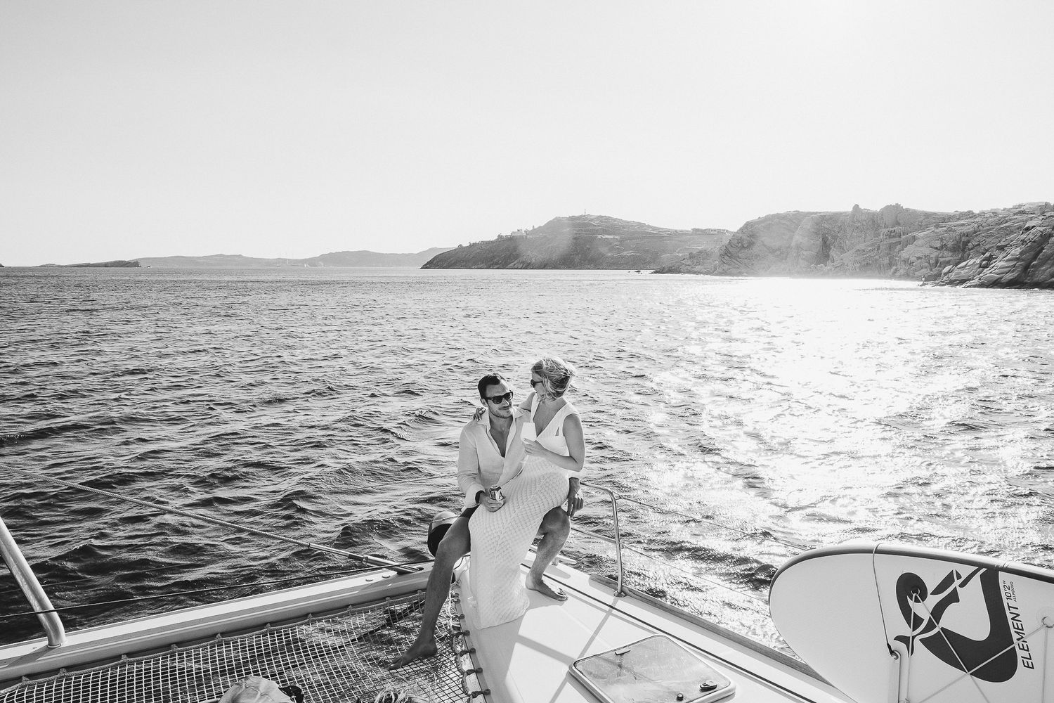 Black and white ocean lifestyle photographs showing people boating and swimming in dramatic seascapes at sunset.