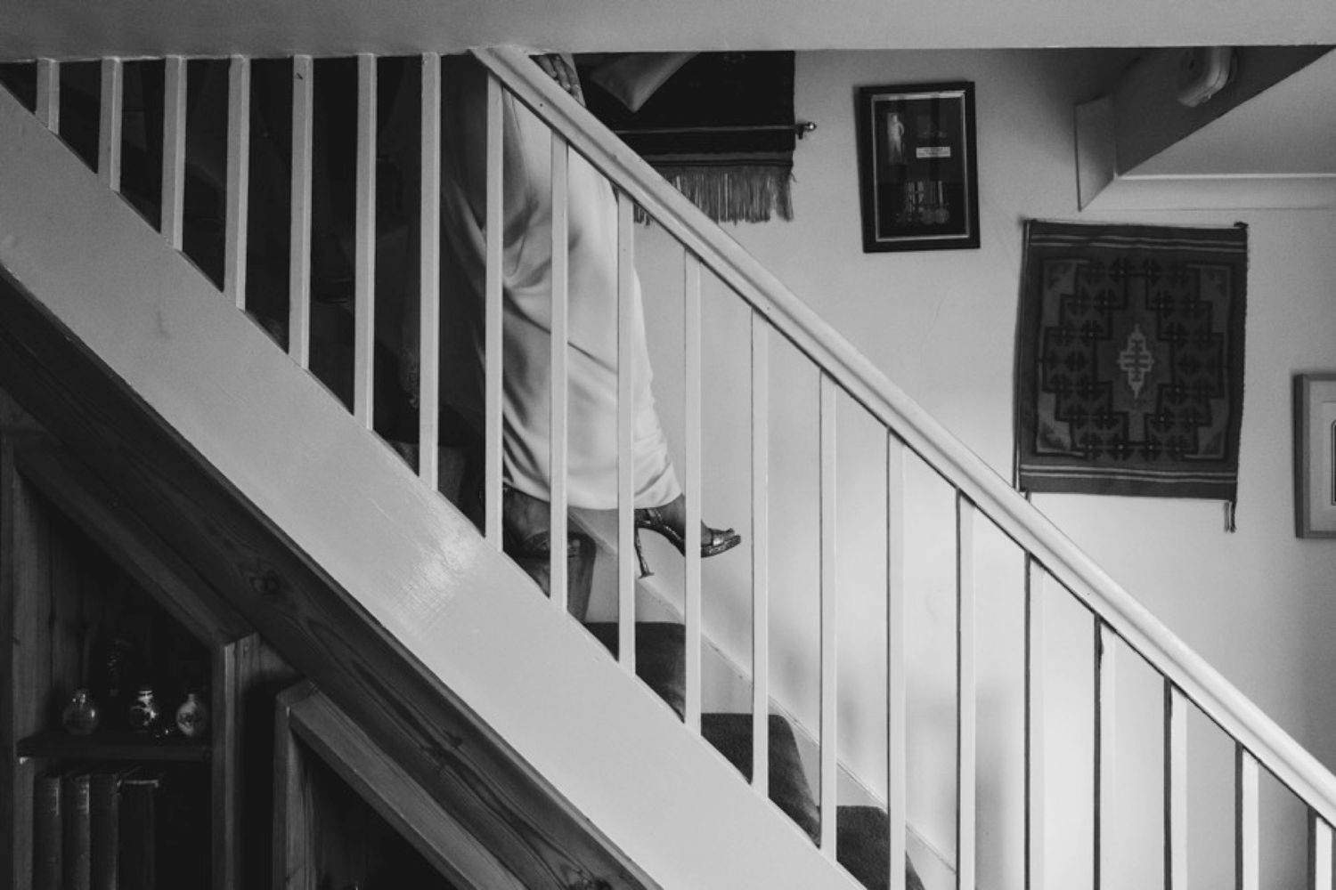 Black and white image of a white staircase with wall art in a residential setting.