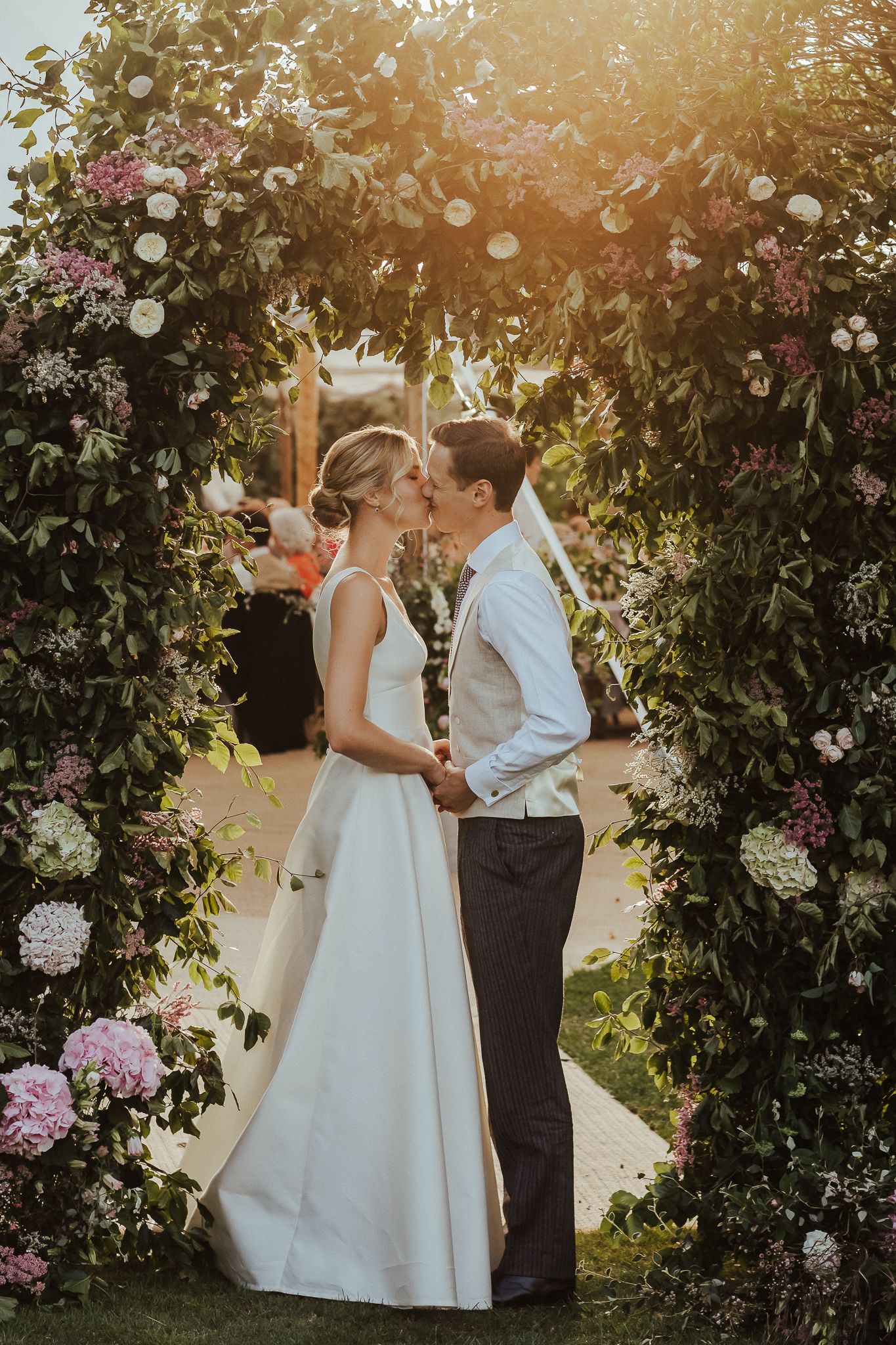 A romantic golden hour garden portrait session with flowering vines creating a natural arch.