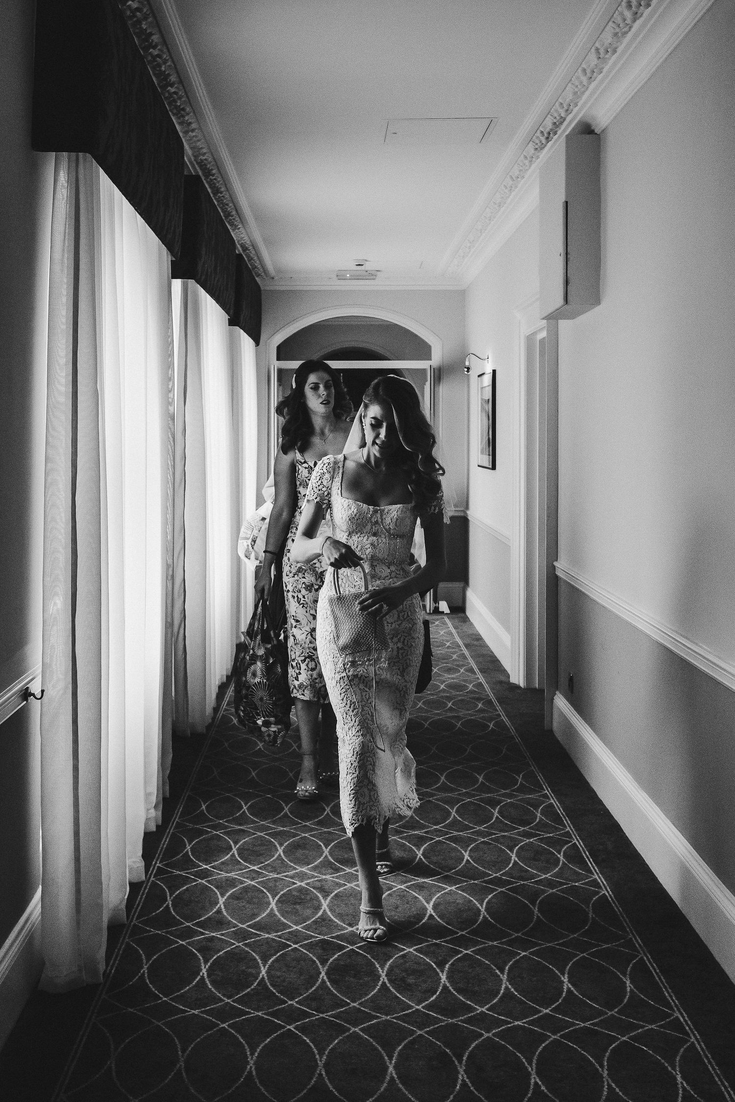 A series of four black and white photos showing people walking down a hotel hallway with patterned carpet.