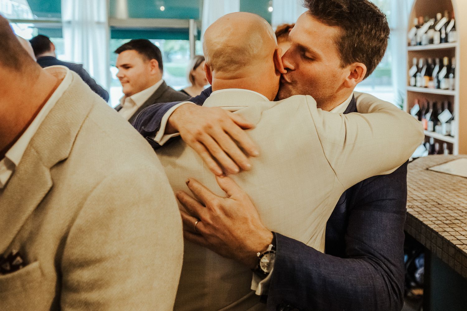 People embracing in a restaurant create a joyful atmosphere of celebration during what appears to be a wedding reception.