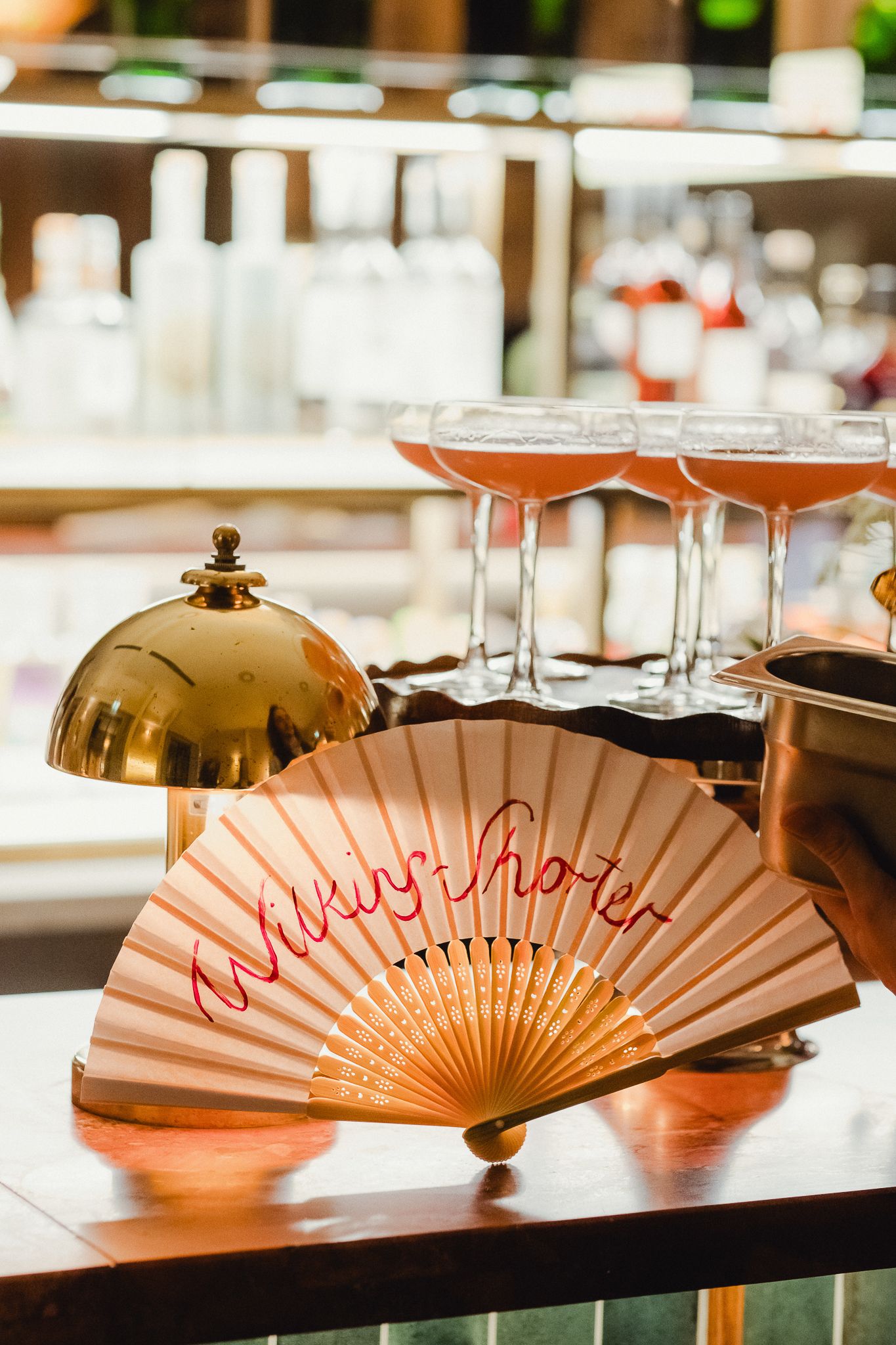 Decorative orange and red paper fans arranged in a row on a dark surface at a wedding reception.