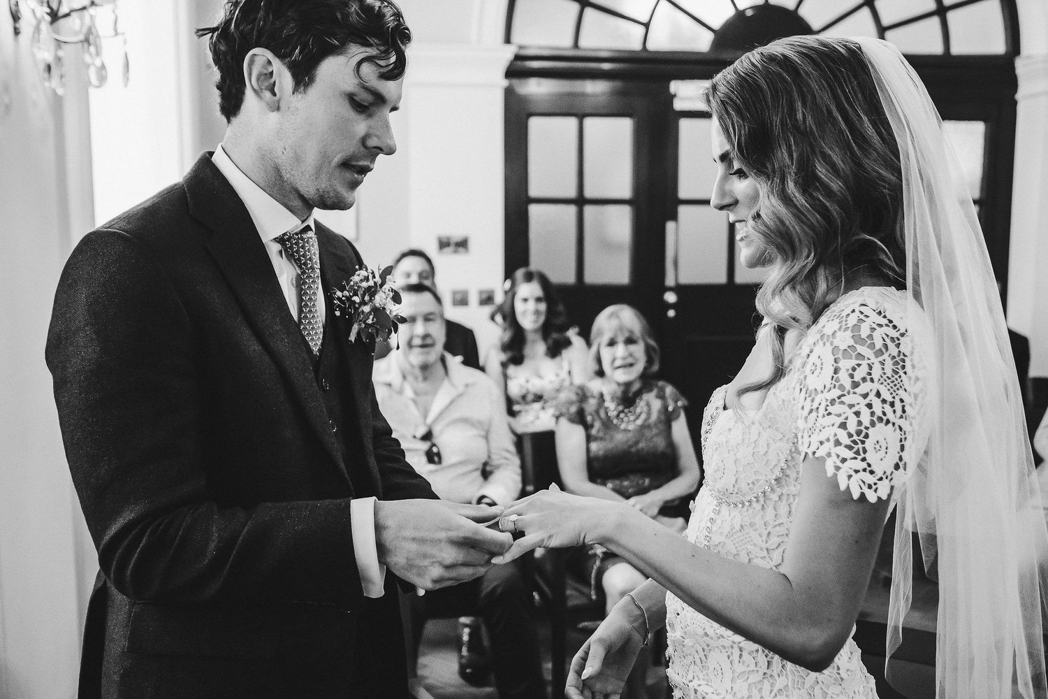 Emotional wedding ceremony moment captured in black and white as rings are exchanged at the altar.