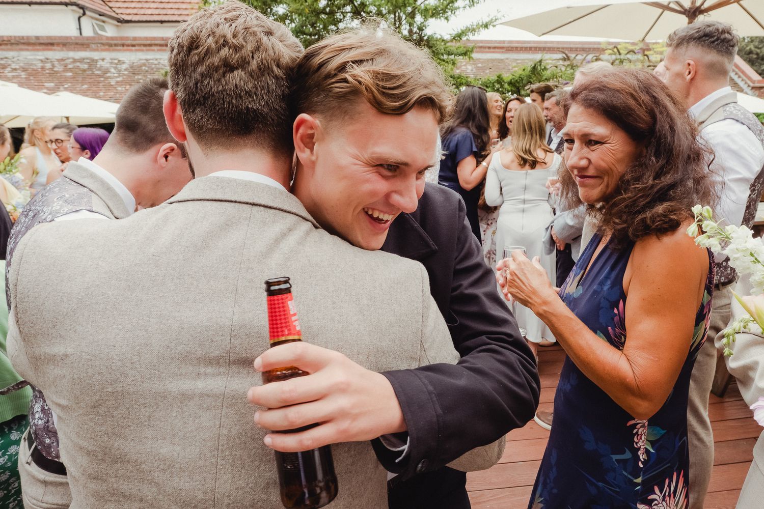 Wedding guests embrace and share emotional moments during an outdoor celebration.