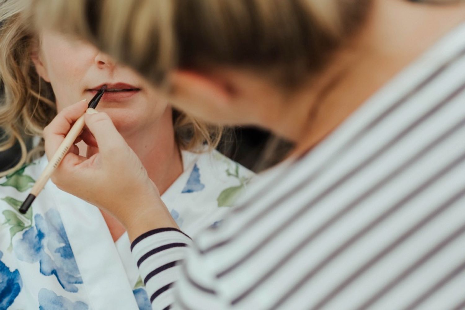 Close-up shot of makeup application with a brush during wedding preparations.