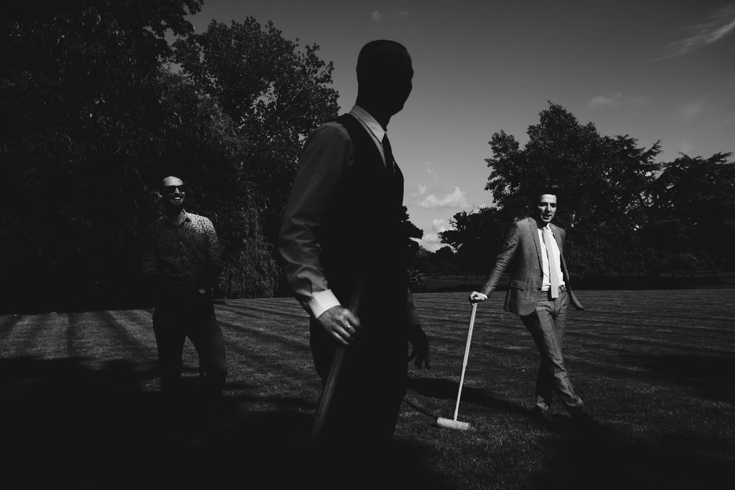 Silhouetted figures playing croquet on lawn at twilight.