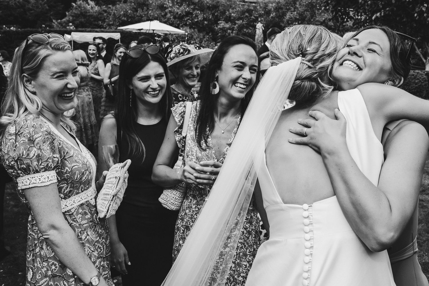Candid moments of wedding guests sharing laughs and embraces during an outdoor celebration.