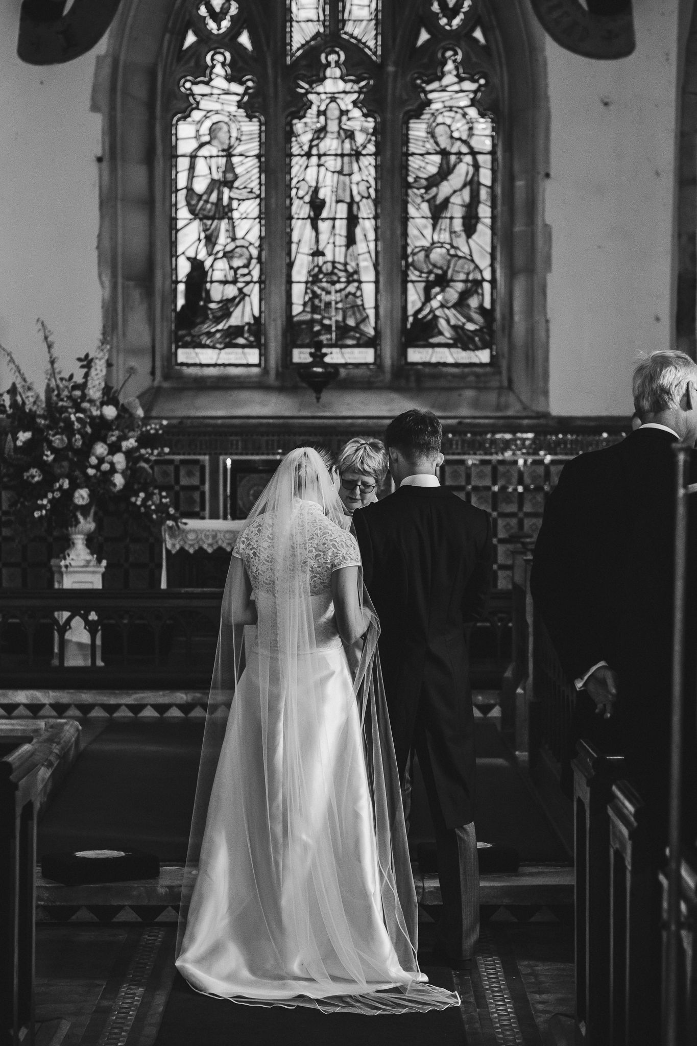 A sequence of four black and white photos showing a bride in a flowing white dress and veil walking in a church aisle.