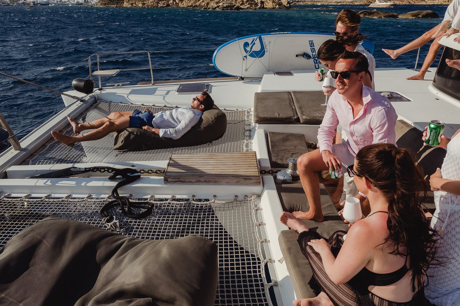 People enjoying a leisure day on a catamaran sailboat deck while relaxing in the sunshine and ocean breeze.