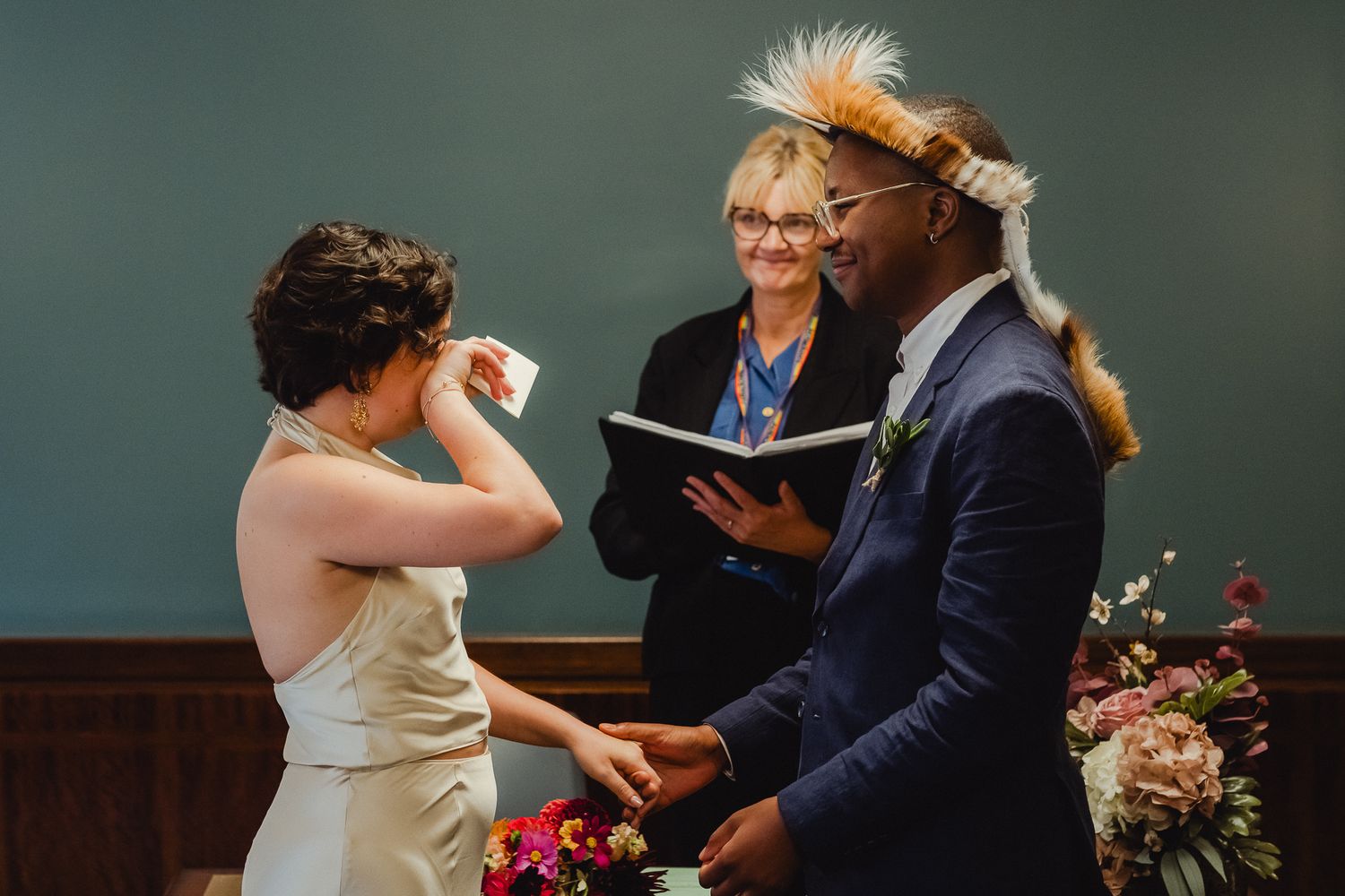 A couple shares a joyful moment during their wedding ceremony with an officiant standing between them.
