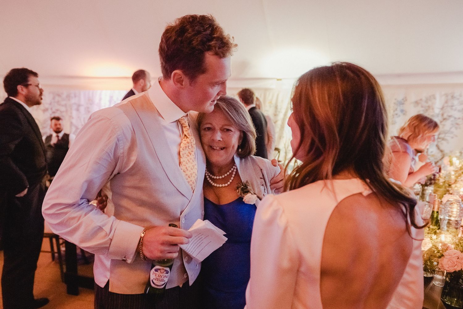 People dancing and celebrating at a lively wedding reception with warm lighting and festive atmosphere.