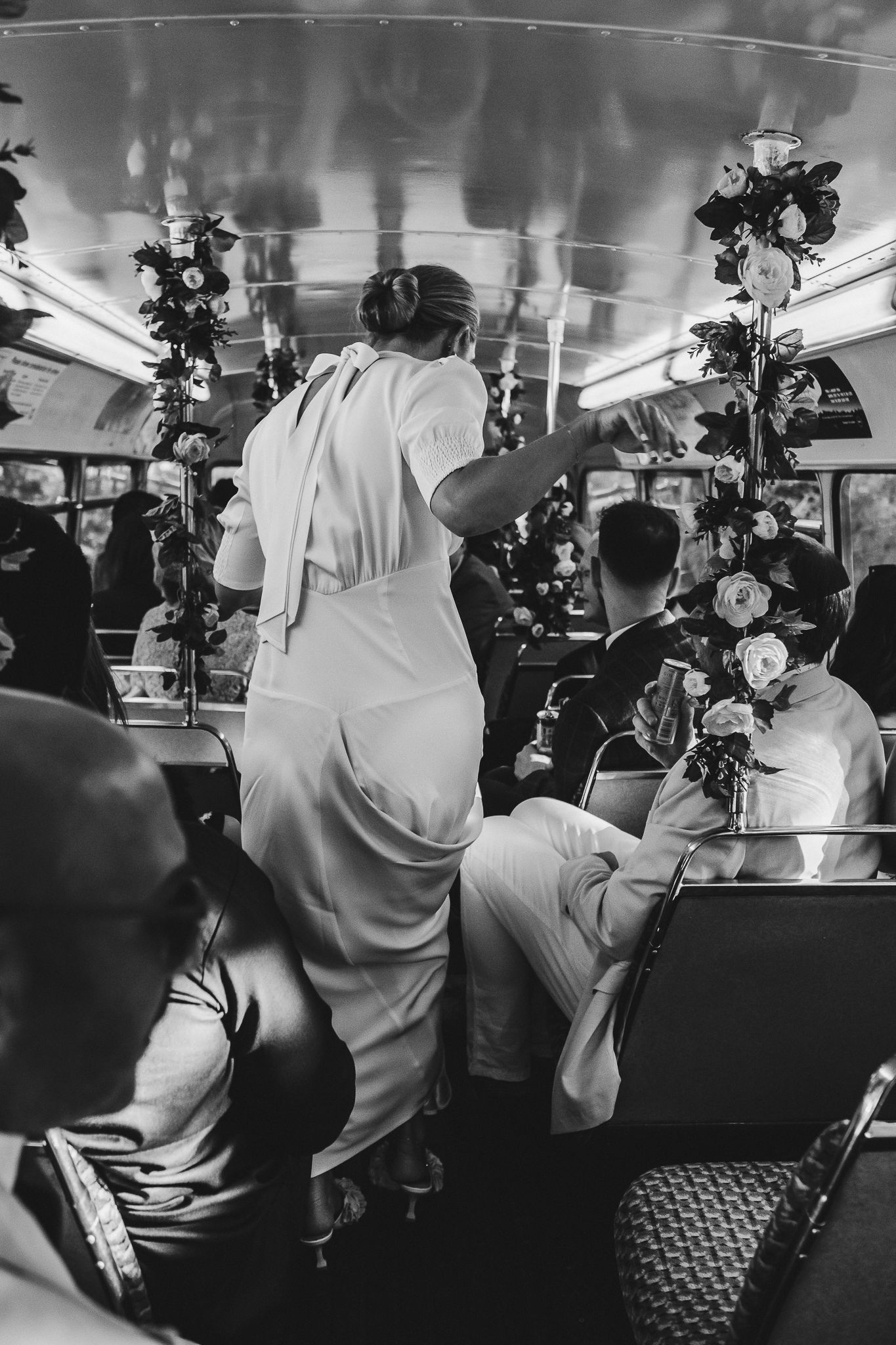 People are gathered inside a train car with Christmas decorations visible in black and white vintage photograph.