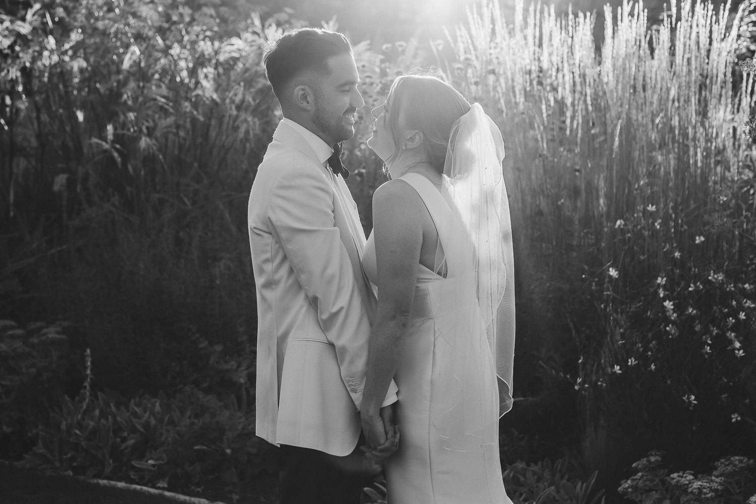 Black and white romantic wedding photos showing couple embracing in a sunlit outdoor garden setting.