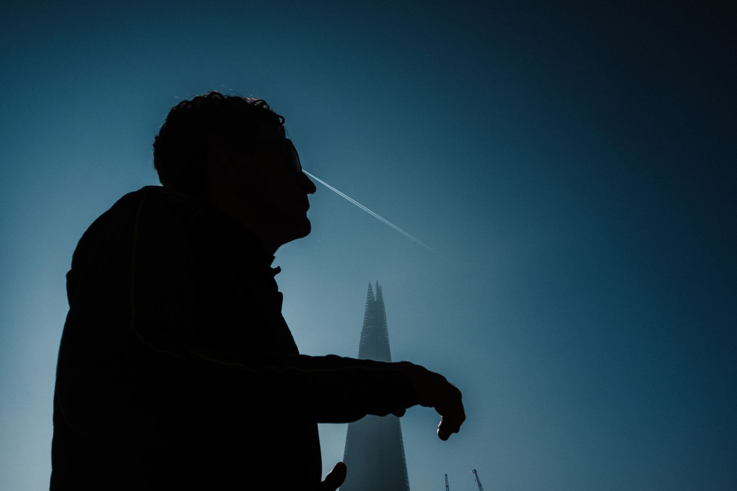 A series of silhouetted figures stand against a dark blue sky with dramatic lighting and shadows.