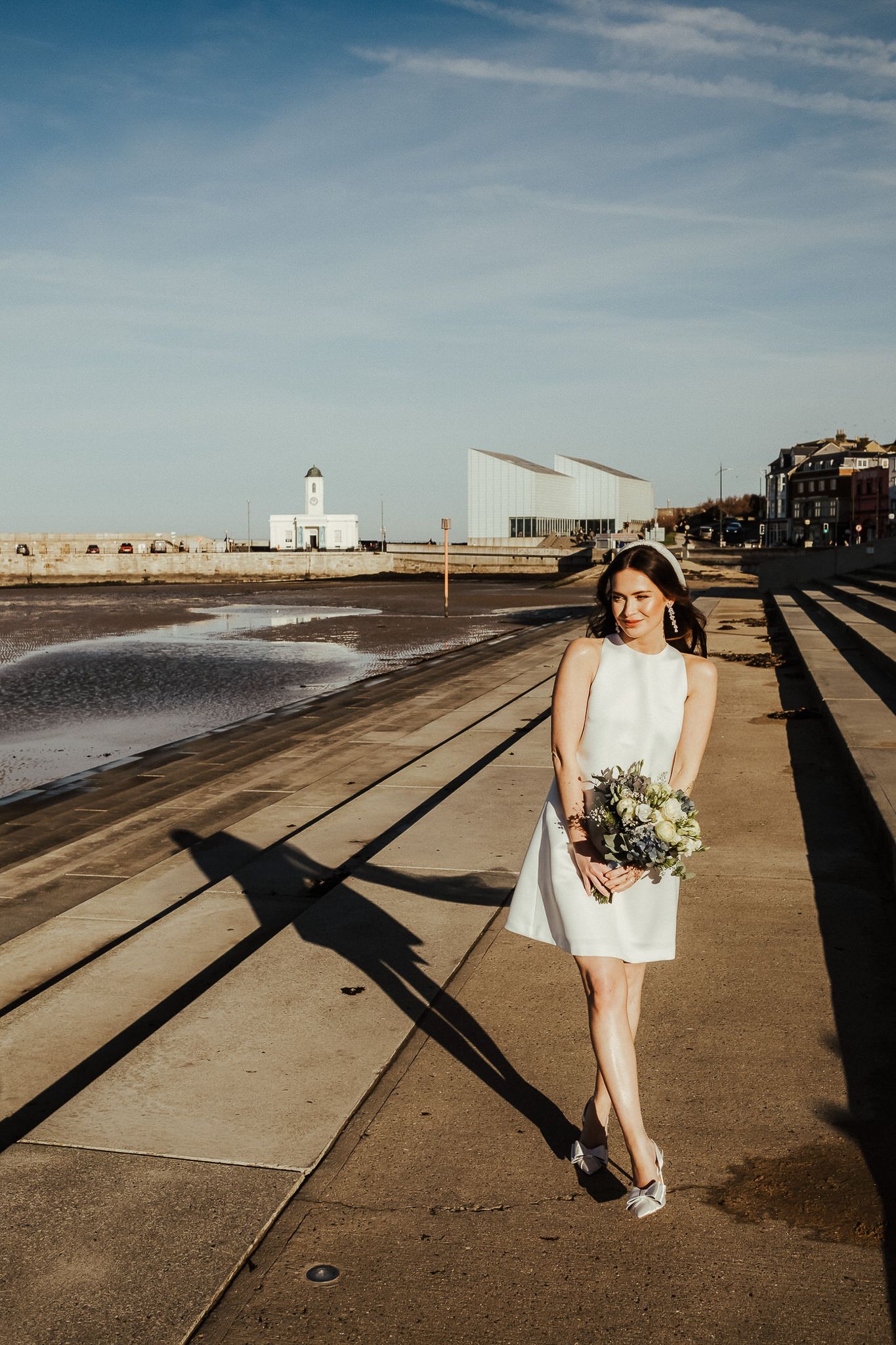 A sequence of seaside photos showing a figure in white walking along a concrete seawall with dramatic shadows and coastal views.