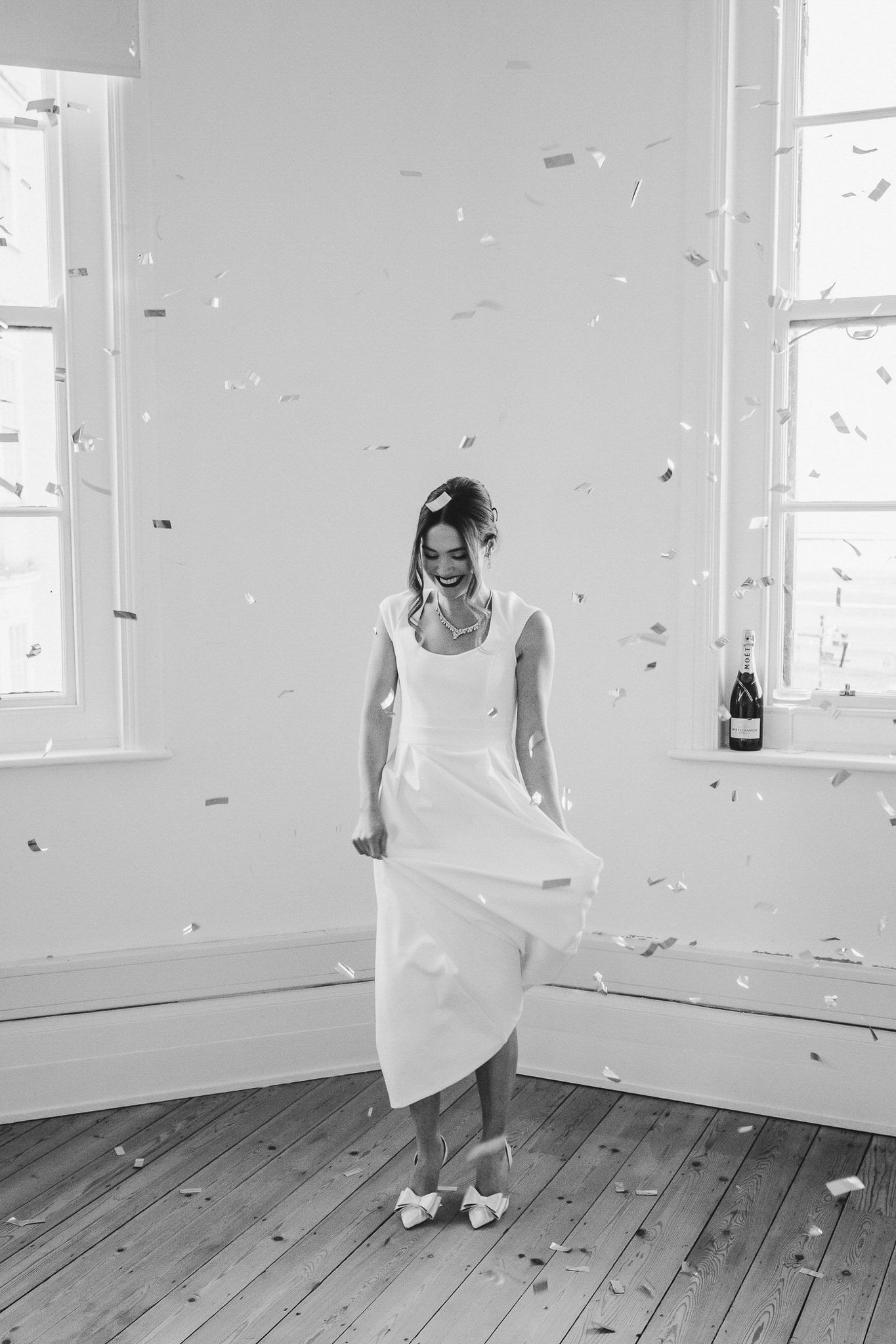 A sequence of black and white photos showing someone dancing and twirling in an empty white room with wooden floors.