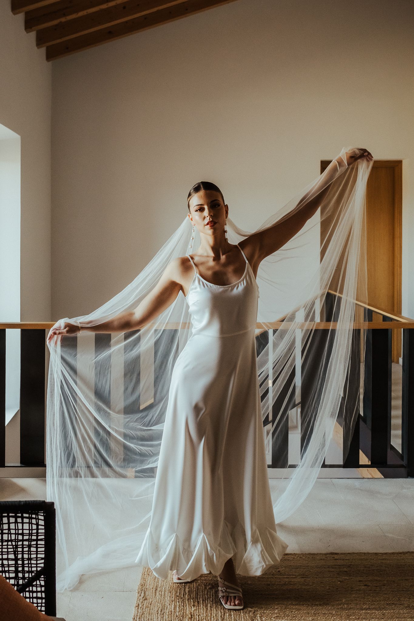 A graceful figure in white moves elegantly with flowing fabric in a series of artistic dance poses against a rustic interior.