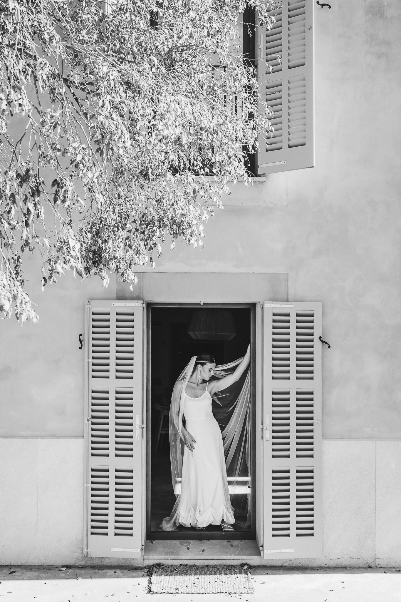 A series of four black and white photos showing white curtains billowing through open shuttered windows against a light wall.