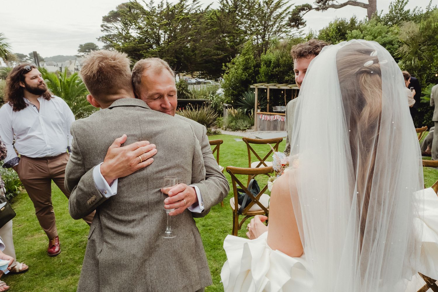 A couple embraces during a romantic outdoor wedding ceremony in a lush garden setting.