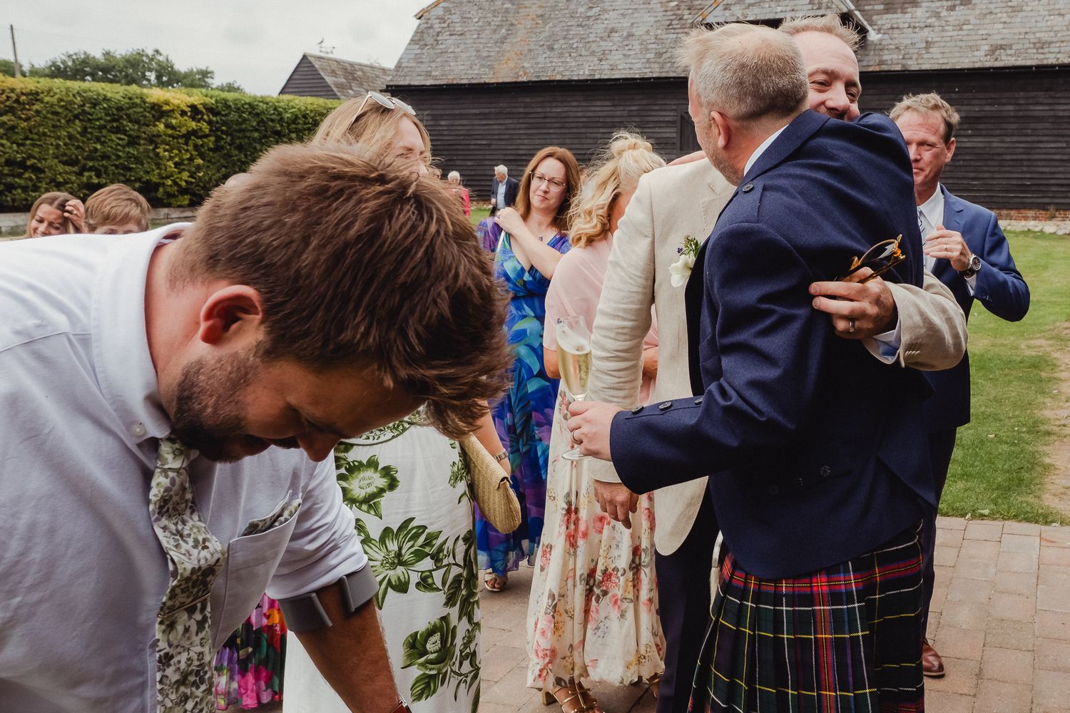 Guests at a Scottish wedding celebration dance and embrace on the outdoor patio during the reception.