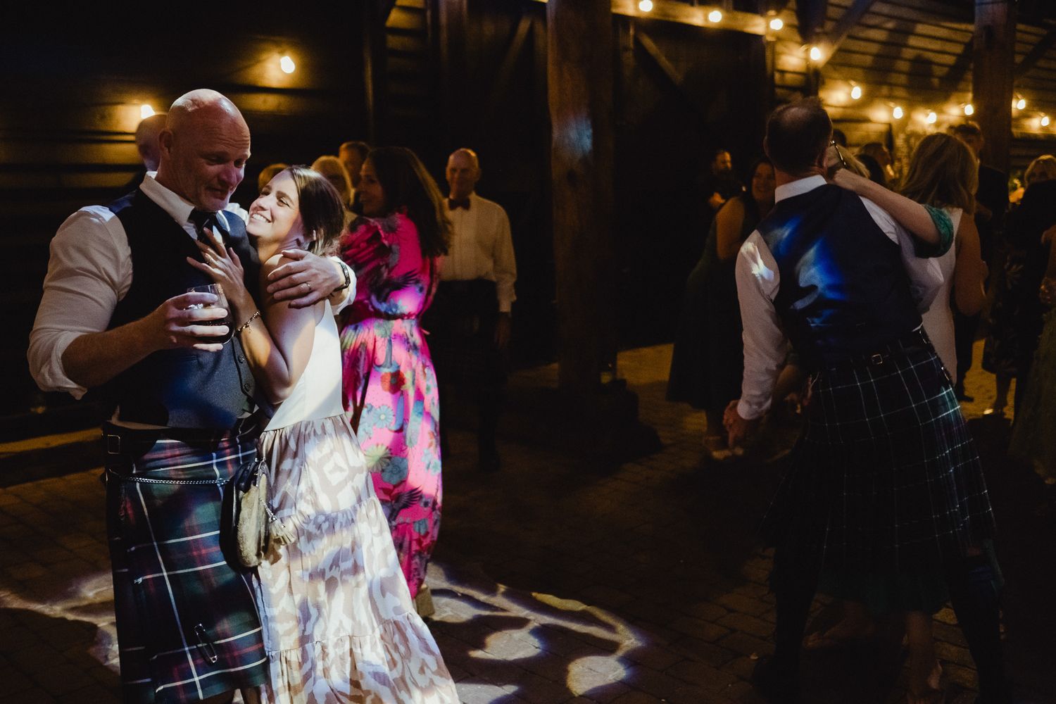 Wedding reception dance party with warm ambient lighting and guests enjoying the festivities.