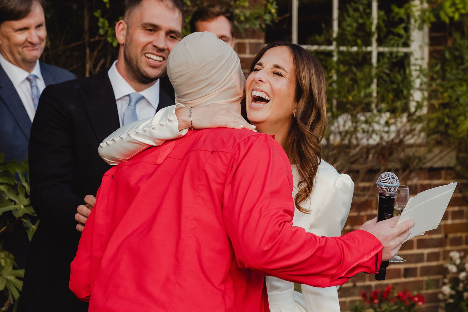 A joyful couple shares a candid moment of laughter while embracing outdoors on a sunny day.
