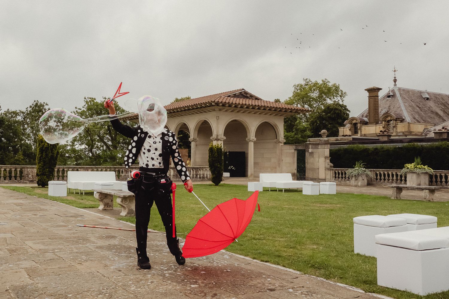A sequence of outdoor photos showing a person with a red umbrella walking through a garden venue.