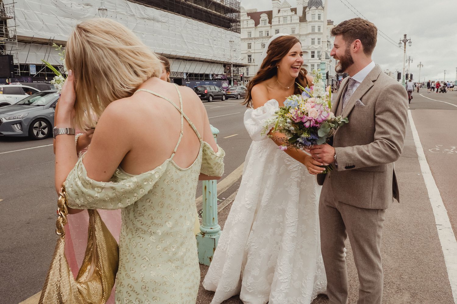 A couple shares a romantic moment during their first look photo session in a parking lot with a floral bouquet.