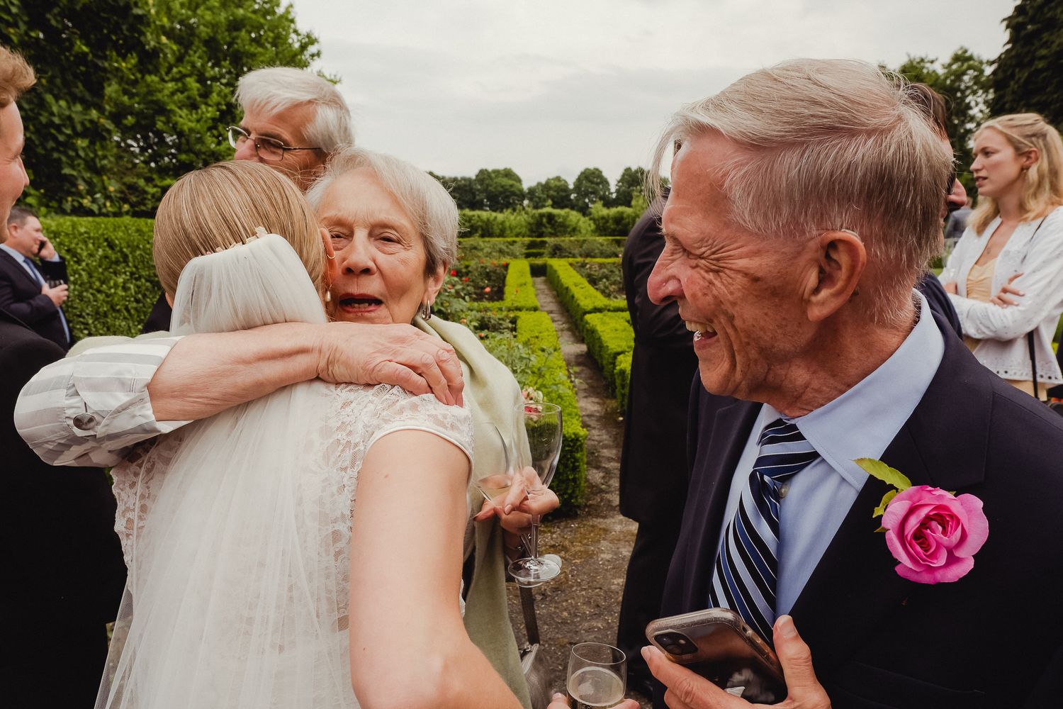 A collection of candid outdoor wedding moments showing guests embracing and celebrating at a garden reception.