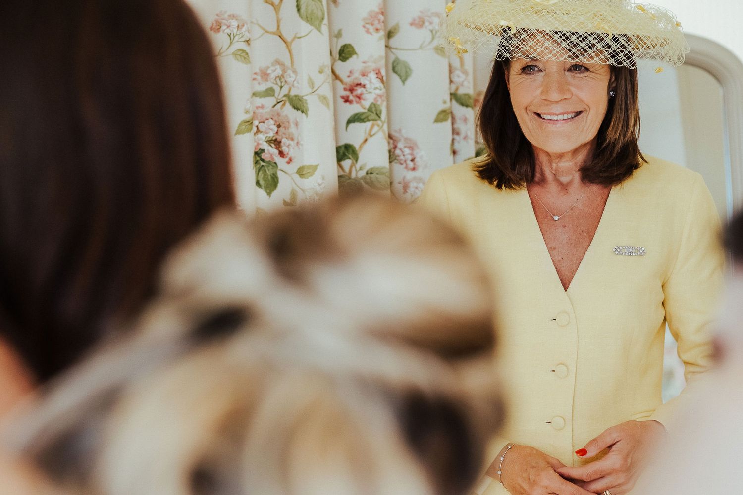 Two people share a joyful moment during wedding preparations in a bright indoor setting.