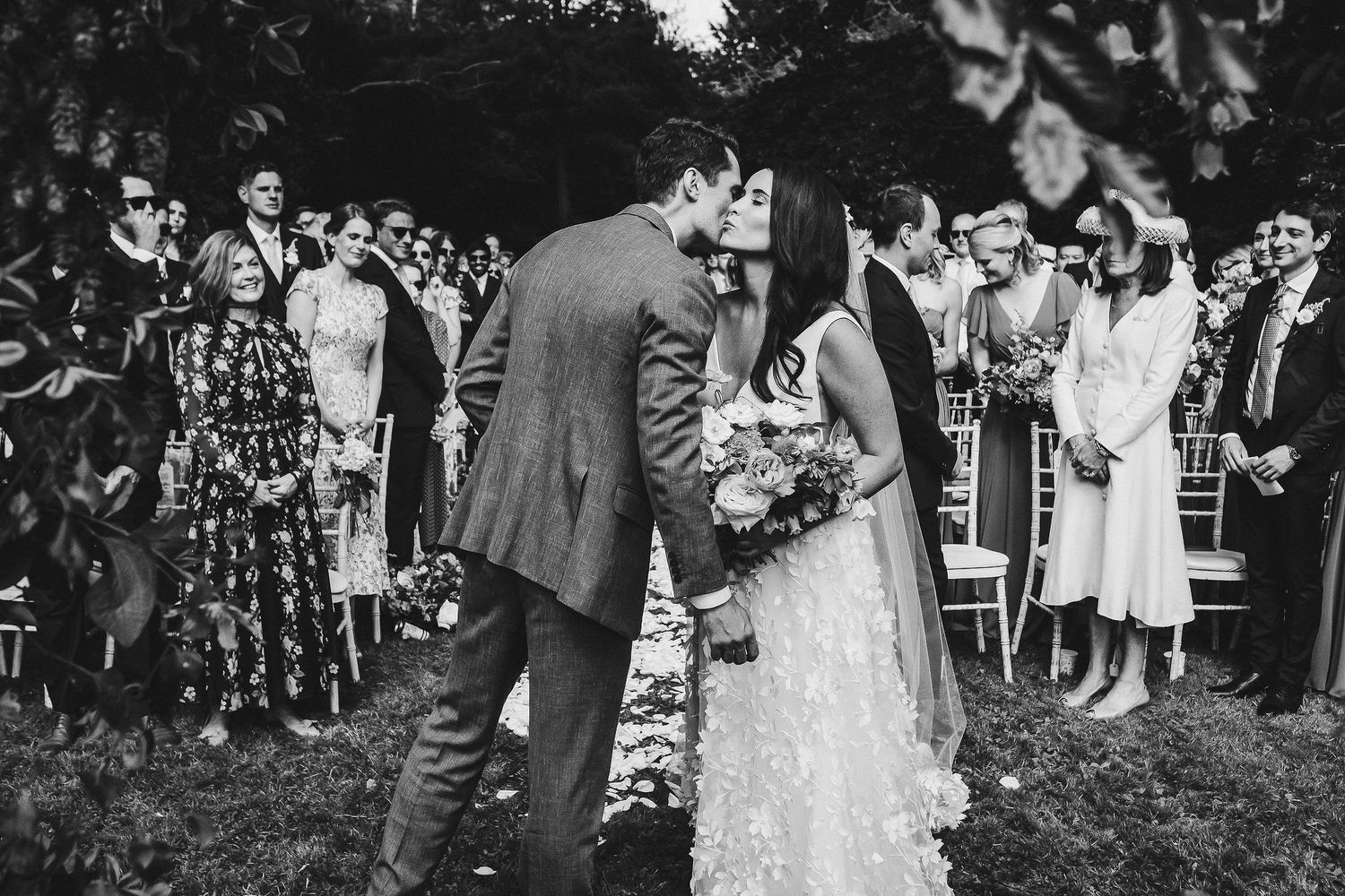 Wedding guests lined up outside to celebrate the newlyweds in a garden setting.