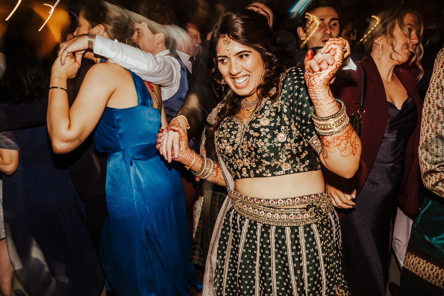 Guests dance and celebrate at a wedding reception in traditional and modern attire.