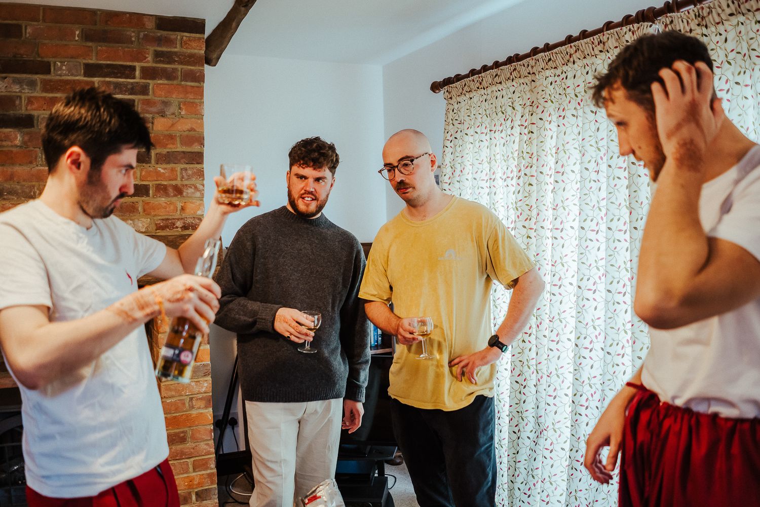 Indoor gathering showing casual interactions between people near exposed brick wall.
