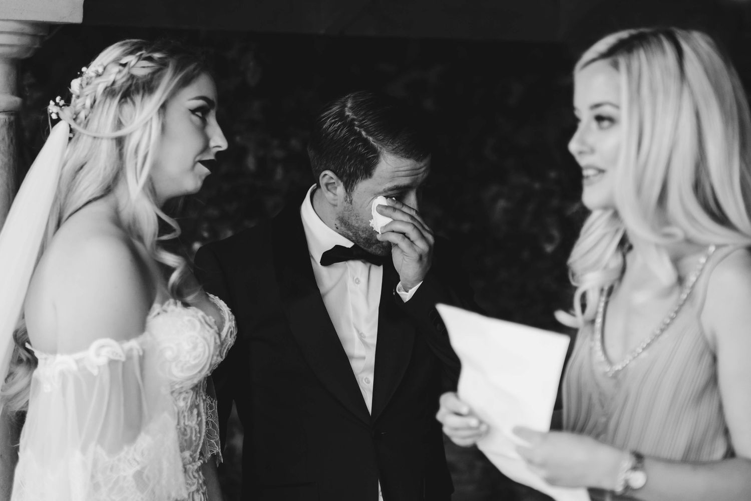 Black and white photo of emotional wedding ceremony with officiant reading vows.