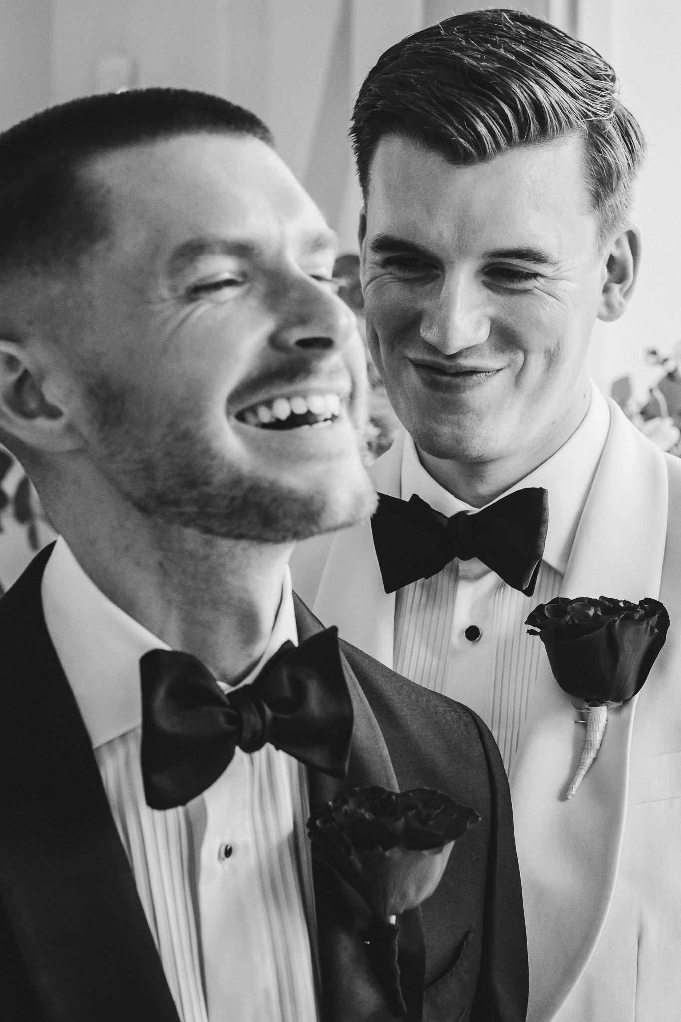 A series of candid black and white photos showing two people in tuxedos sharing intimate laughing moments together.