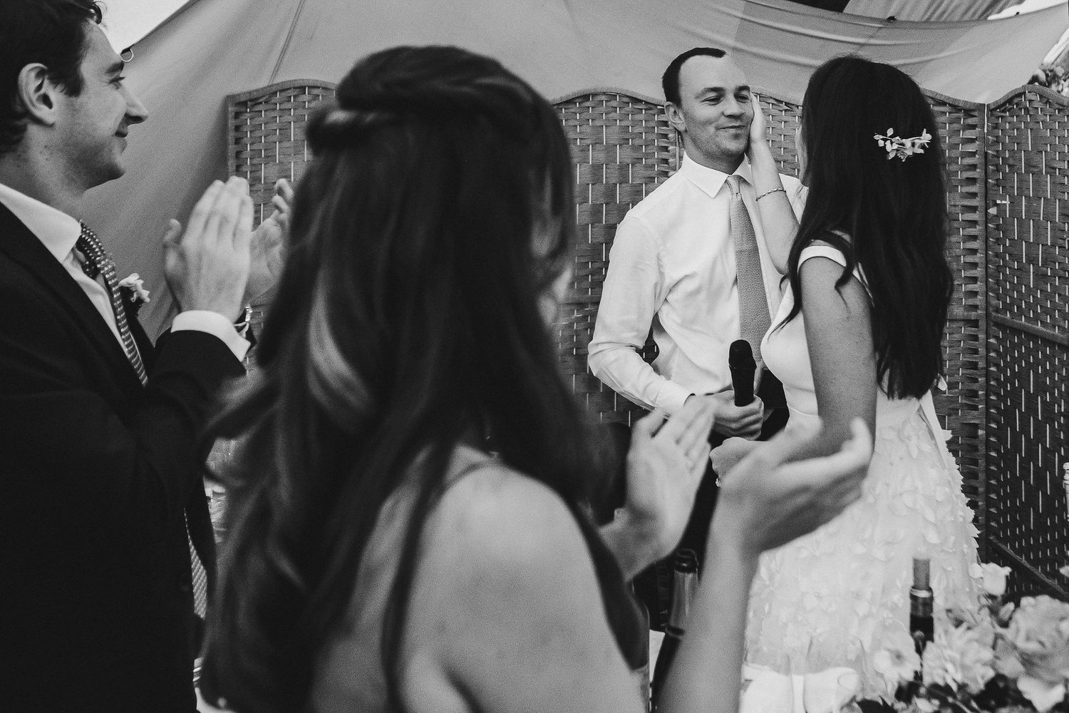Black and white photo of wedding guests sharing animated conversation at reception.